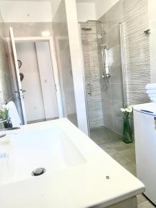 ein weißes Bad mit einer Dusche und einem Waschbecken in der Unterkunft Villa Roso in Kaštela