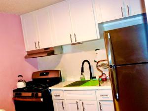 a kitchen with white cabinets and a stainless steel refrigerator at Think Pink in Fort Worth