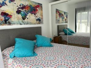 a bedroom with a bed with blue pillows and a mirror at Apartamento Postman in Arenales del Sol