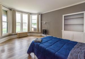 um quarto com uma cama azul num quarto com janelas em Port Huron Temp Stays - Apartment 1 em Port Huron