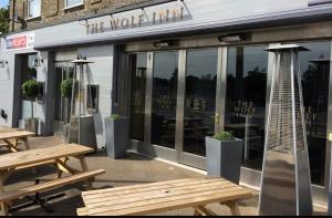 a restaurant with wooden benches in front of a building at Wolf Inn Serviced Accommodation in Lowestoft