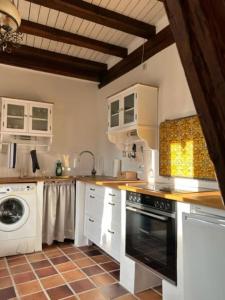eine Küche mit weißen Schränken, einer Waschmaschine und einem Trockner in der Unterkunft Gemütliches Scheunenfachwerkhaus in Bad Soden am Taunus