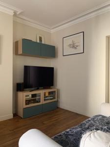 a living room with a flat screen tv on a stand at Chambre Quartier Auteuil in Paris