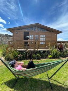 une femme allongée dans un hamac devant une maison dans l'établissement Eco Cabaña Guayacán Ráquira, à Ráquira