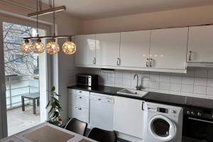 kuchnia z białymi szafkami, zlewem i zmywarką do naczyń w obiekcie Private Apartment w Hanowerze