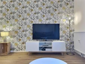 a living room with a tv and a flower wallpaper at ''Douceur'' de Miss.K Conciergerie in Mâcon
