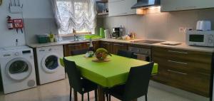 een keuken met een groene tafel met stoelen en een wasmachine bij Central Studio Apartment in Msida