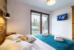 two beds in a room with a window at ARAMIKA apartamenty in Szklarska Poręba