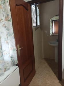 uma casa de banho com uma porta de madeira e um lavatório em PENSIÓN CARLOS III em Tomelloso