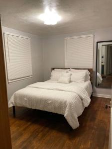 a bedroom with a bed with white sheets and a mirror at Cozy 4 bd house in Pitt in Pittsburgh