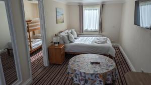 a small bedroom with a bed and a table at Ivybridge Guesthouse in Fishguard