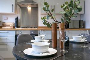 a table with plates and wine glasses on it at Ashworth House by Truestays - NEW 3 Bedroom House in Failsworth, Manchester in Manchester