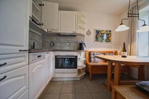 une cuisine avec des appareils électroménagers blancs et une table avec des verres à vin dans l'établissement Wohnung-Suedwind, à Süddorf 3 autres photos