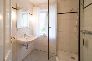 une salle de bain blanche avec un lavabo et une douche dans l'établissement Wohnung-Suedwind, à Süddorf