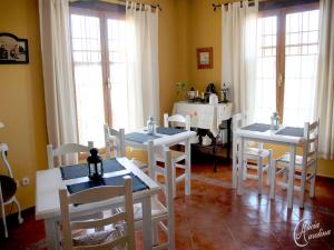 uma sala de jantar com mesas e cadeiras brancas e janelas em Hotel Boutique Alicia Carolina em Monachil