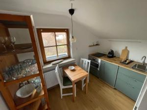 a small kitchen with a wooden table and a table and chairs at Ferienwohnung am Moosbach in Anger
