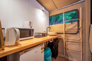 eine Küche in einem Wohnwagen mit einer Theke und einer Mikrowelle in der Unterkunft Deluxe King Safari Tent 2 in Nelly Bay