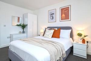 a bedroom with a large white bed with orange pillows at Denton House by Truestays - NEW 3 Bedroom House in Manchester in Manchester