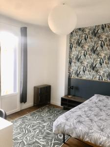 ein Schlafzimmer mit einem Bett und einer gemusterten Wand in der Unterkunft Chambre à Sigoules dans maison partagée in Sigoulès