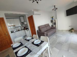 ein Wohnzimmer mit Tisch und Stühlen und einer Couch in der Unterkunft Apartamentos Playacala in La Cala del Moral