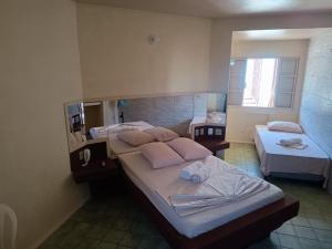 a room with three beds and a mirror at Hotel Comodoro De Livramento in Santana do Livramento