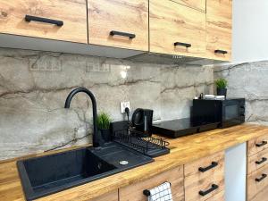 a kitchen with a black sink and a microwave at MMRent Waterfall Room in Gdańsk
