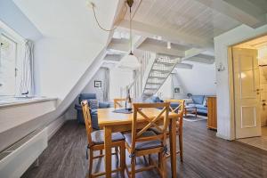 a dining room with a table and chairs and a staircase at Wohnung-Landwind in Süddorf