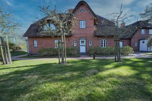 a large red brick house with trees in the yard at Lycka-Hues in Norddorf