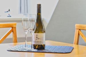 a bottle of wine sitting on a table with two glasses at Wohnung-Landwind in Süddorf +8 photos