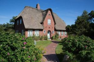 a large red brick house with a thatched roof at Wohnung-Landwind in Süddorf