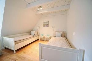 a bedroom with two beds and two tables at Lycka-Hues in Norddorf