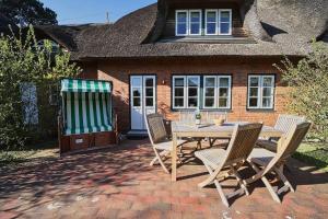 a wooden table and chairs in front of a house at Lycka-Hues in Norddorf