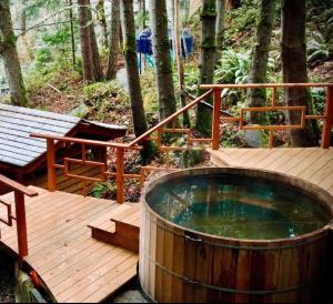 a wooden deck with a hot tub and a bench at Sungate on Salt Spring BnB in Salt Spring Island