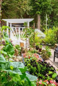 a garden with flowers and a greenhouse in the background at Sungate on Salt Spring BnB in Salt Spring Island