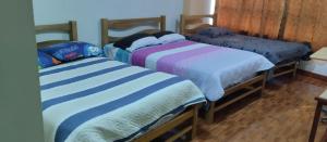 Habitación con 2 camas individuales y suelo de madera. en Hostal Panoramic, en Churín