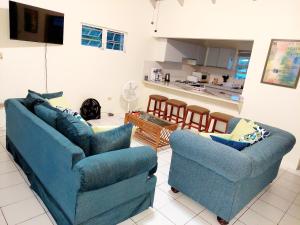 a living room with two blue couches and a kitchen at Beautiful 2-Bedroom Near Airport - Powell's Main Road, Antigua in Carlisle