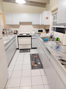 a white kitchen with white cabinets and a stove at Beautiful 2-Bedroom Near Airport - Powell's Main Road, Antigua in Carlisle