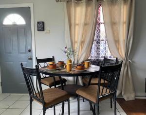 a dining room table with chairs and a table with dishes on it at 1 Bedroom Apartment, in Coconut Drive San Fernando in San Fernando