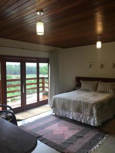 sypialnia z łóżkiem i przesuwnymi szklanymi drzwiami w obiekcie Villa Uliana - Bangalôs VILLA w mieście Domingos Martins