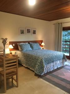 1 dormitorio con 1 cama y 1 mesa con 2 lámparas en Villa Uliana - Bangalôs VILLA en Domingos Martins