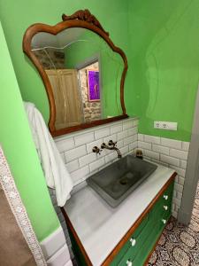 a green bathroom with a sink and a mirror at Habitación de 1870 in Santiago de Compostela