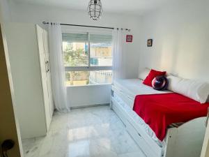 una camera da letto con un letto con una coperta rossa e una finestra di Bonito apartamento de la playa a Villajoyosa