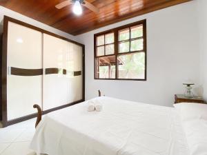 1 dormitorio con 1 cama blanca y 2 toallas en Casa de Pedra - Canasvieiras, en Florianópolis