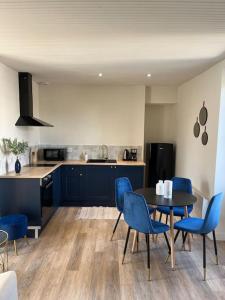 a kitchen with a table and some blue chairs at *CASA Ushuaia* in Cholet +16 photos