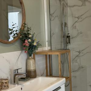 a bathroom sink with a mirror and a vase with flowers at Le Clos Du Moulin 3 - Maison et Jardin, proche Avignon en Provence in Entraigues-sur-la-Sorgue