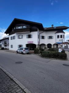 a white building with a car parked in front of it at LELA Apartments Chiemsee in Bernau am Chiemsee