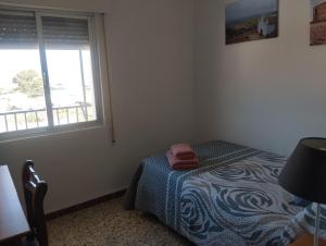 a bedroom with a bed with a blue blanket and a window at Apartamento Las Fuentes in Sierra de Fuentes