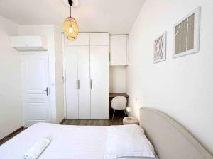 ein weißes Schlafzimmer mit einem Bett und einem weißen Schrank in der Unterkunft Le Bruna: Apt 4 prs, Clim, 10 min plages in Antibes