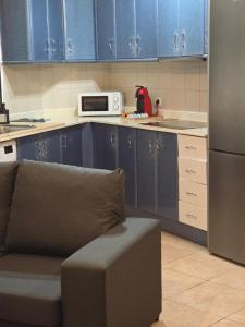 uma cozinha com armários azuis, um sofá e um micro-ondas em Casa Maday em Cotillo