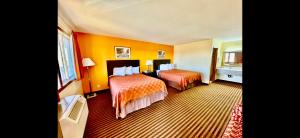 a hotel room with two beds with orange walls at Scottish Inn & Suites - Eau Claire in Eau Claire